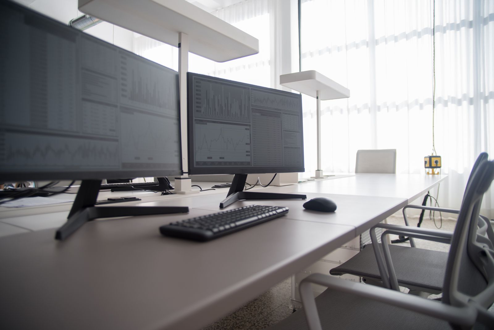 Poste de travail avec double écran et chaise de bureau dans un bureau lumineux