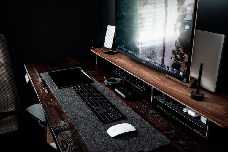 Bureau en bois massif avec double écran et accessoires, ambiance sombre premium