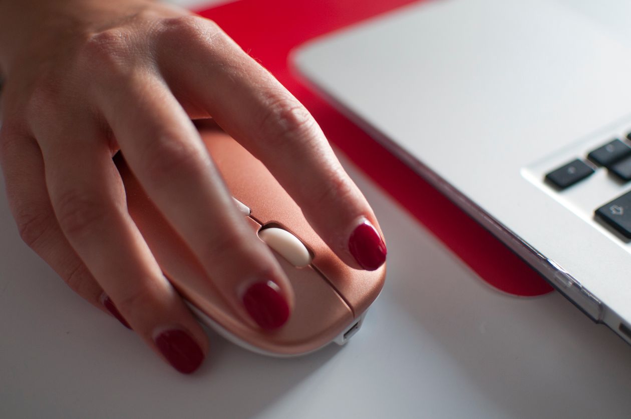 Main sur une souris d'ordinateur près d'un ordinateur portable