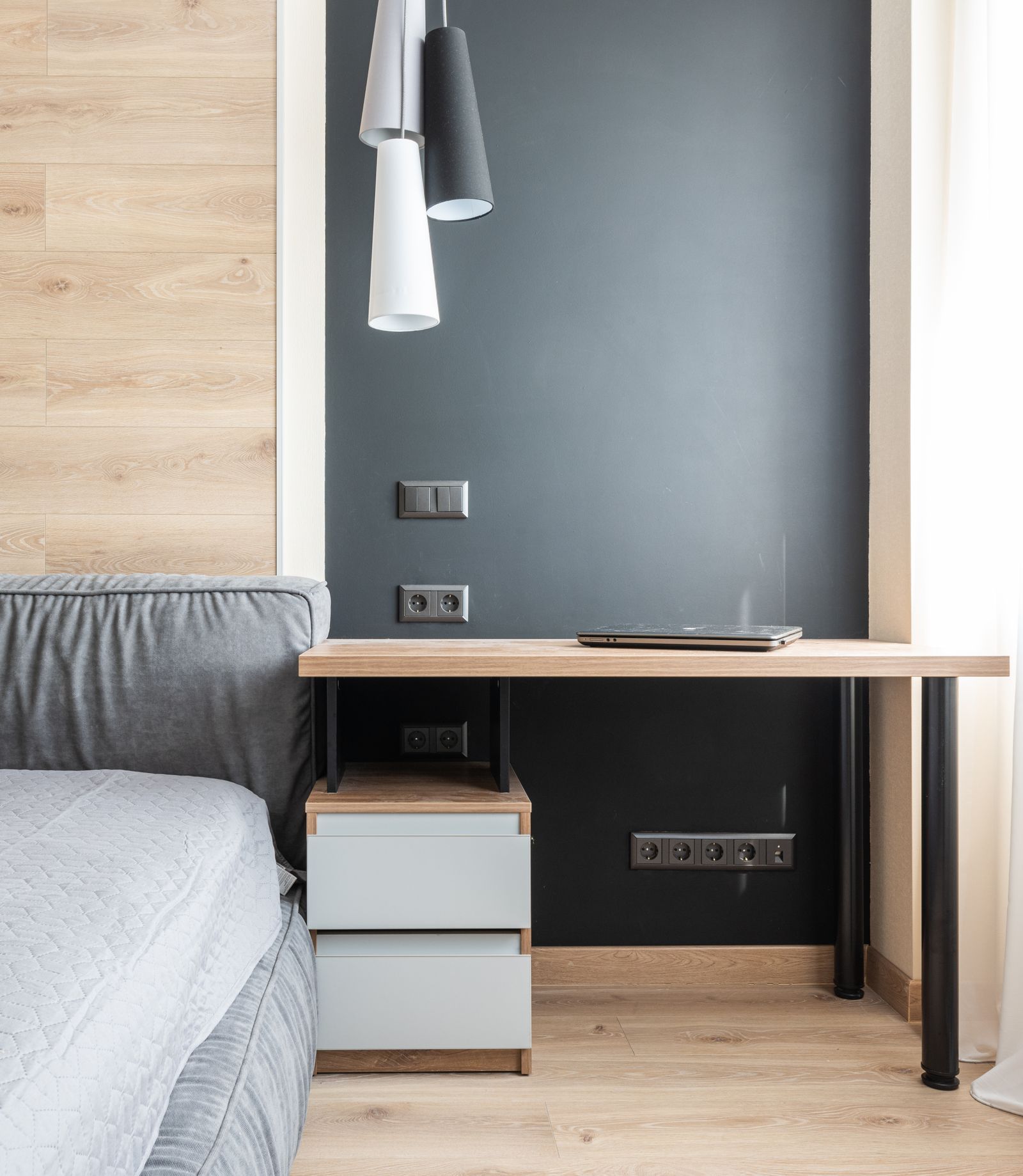 Petit bureau droit décor chêne avec caisson de tiroirs, installé au bout d’un lit