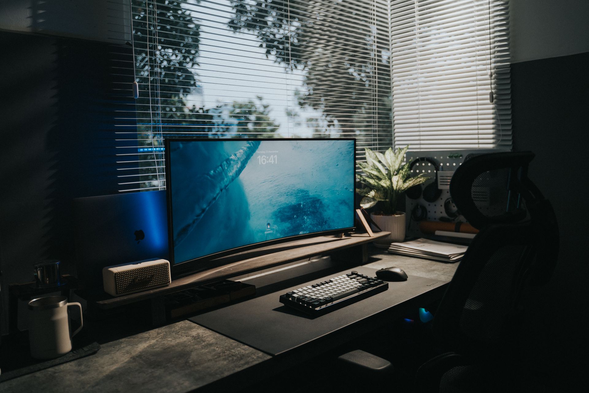 Setup de bureau assis-debout avec écran incurvé, plante et clavier mécanique