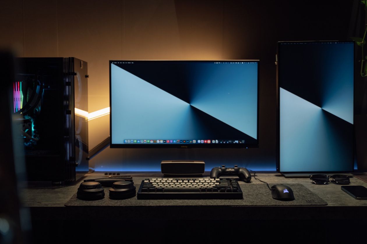 Bureau avec double écran, tour PC et clavier mécanique, ambiance sombre