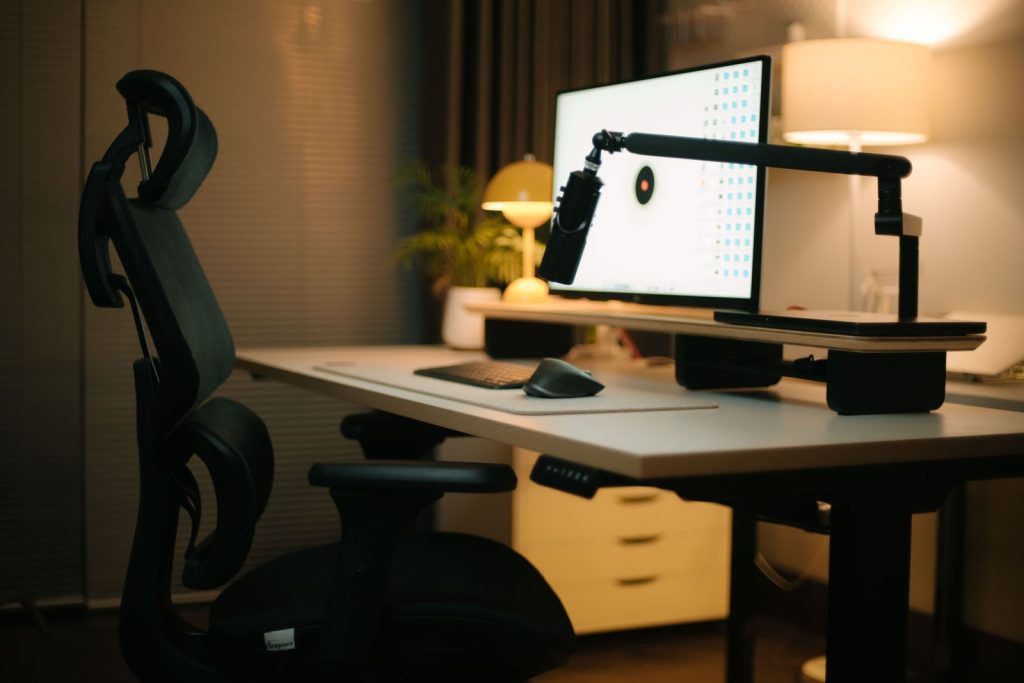 Écran fixé sur un bras articulé au-dessus d'un bureau, avec un fauteuil ergonomique