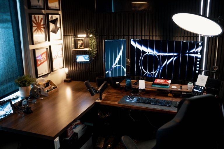 Bureau d'angle en bois foncé installé dans un coin de pièce, avec deux écrans
