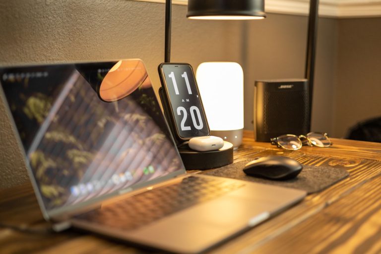 Bureau en bois avec une lampe, un téléphone posé sur un support de charge et un ordinateur portable