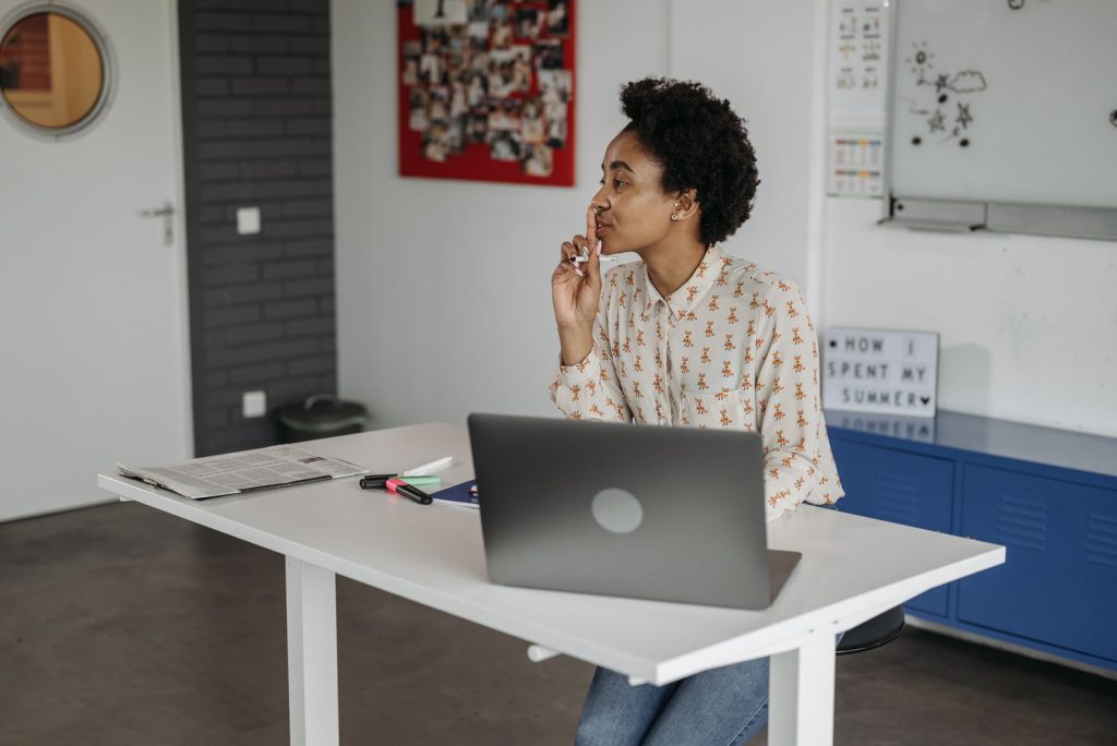 Femme à un bureau réglable blanc en position haute, devant un ordinateur portable
