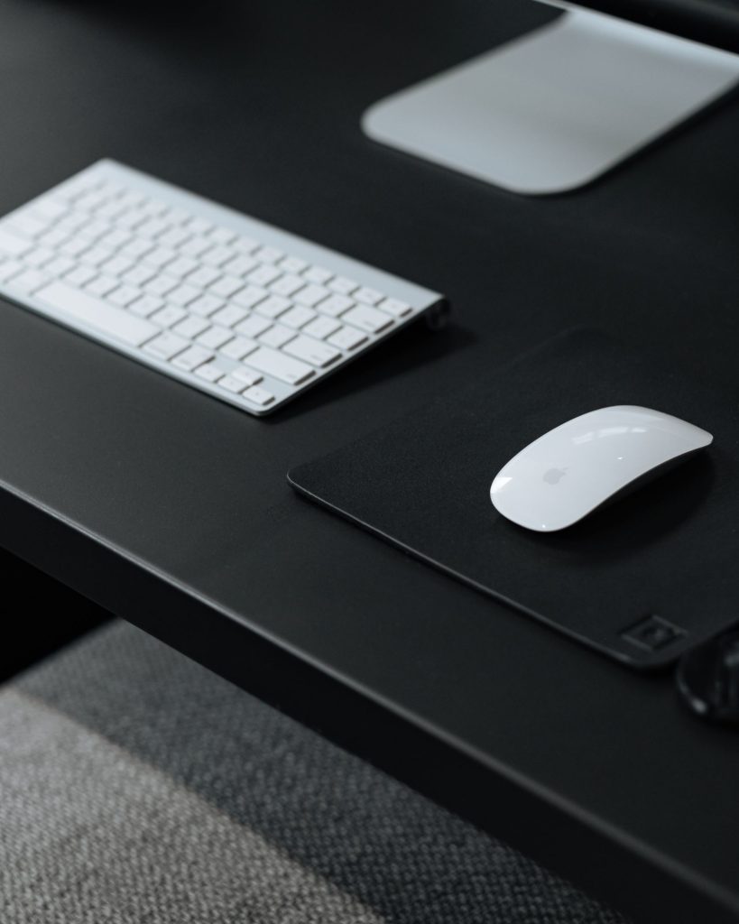 Clavier et souris blancs posés sur un plateau de bureau noir mat